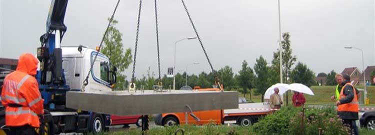 Transport en plaatsing van de betonnen fundering voor een stalen beeld op een rotonde in Gorinchem.