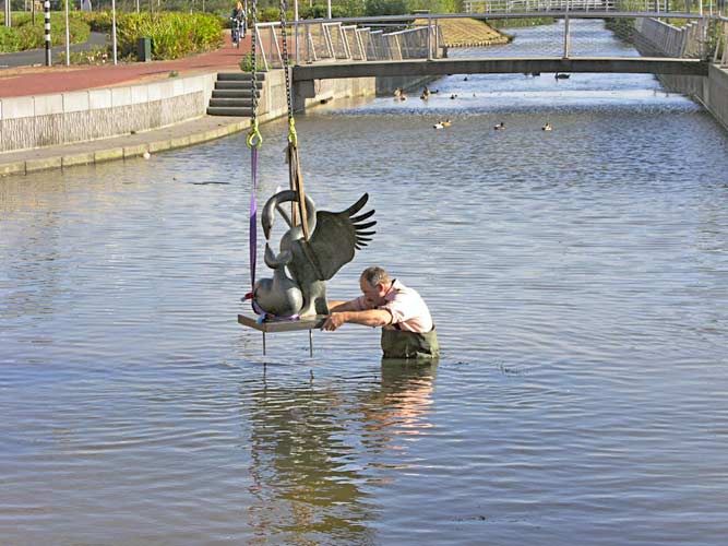 plaatsing van een bronzen beeldvan Evert den Hartog in een vijver