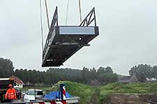 De voetbrug voor de Chladni Vijver van het omgevingskunstwerk van Paul de kort in Buitenschot gaat op transport.